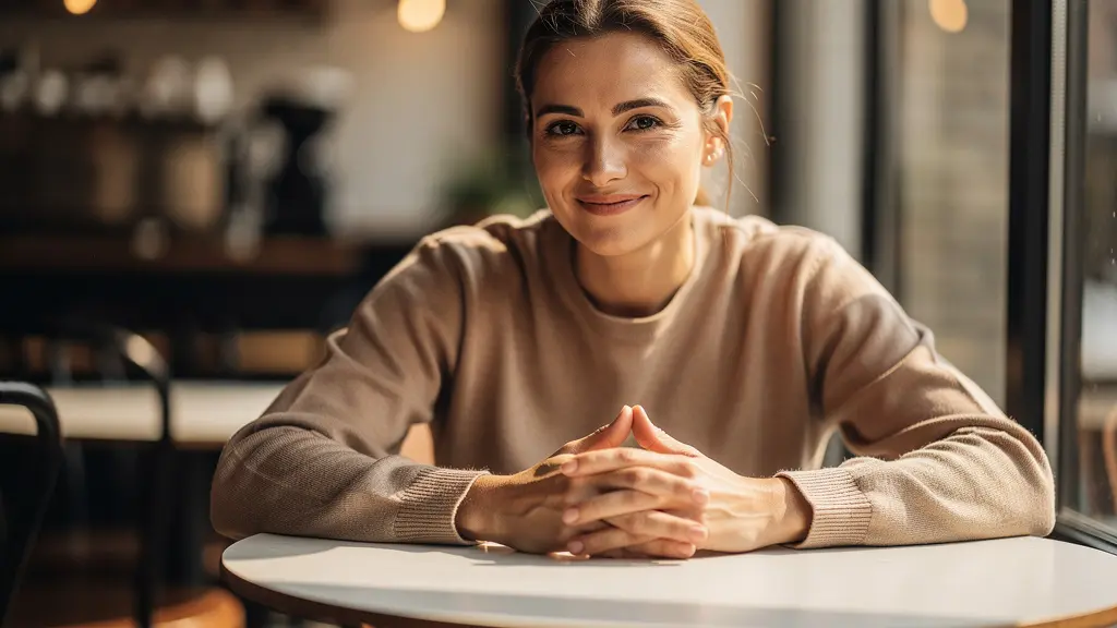 Portrait d'une personne sereine avec les mains posées naturellement sur une table de café, posture ouverte et relaxée